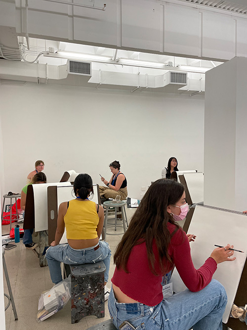 students sitting on drawing horses preparing for class to start